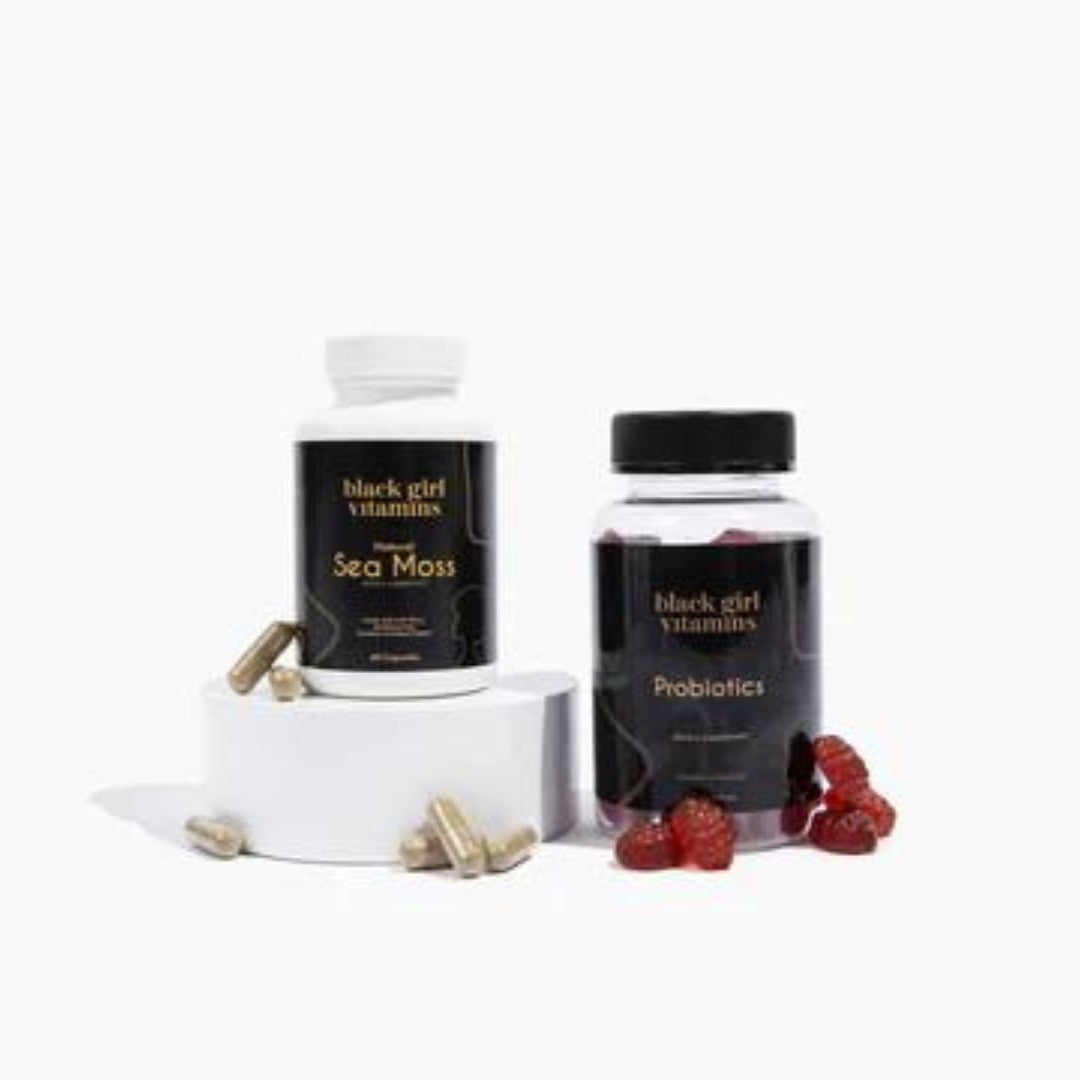 Two supplement bottles labeled 'black girl vitamins Sea Moss' and 'black girl vitamins Probiotics' with capsules and red gummy supplements.